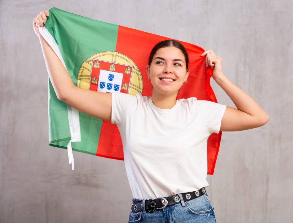 Jovem sorridente segurando a bandeira de Portugal, simbolizando o caminho para a cidadania portuguesa através de naturalização, casamento, descendência ou dupla nacionalidade